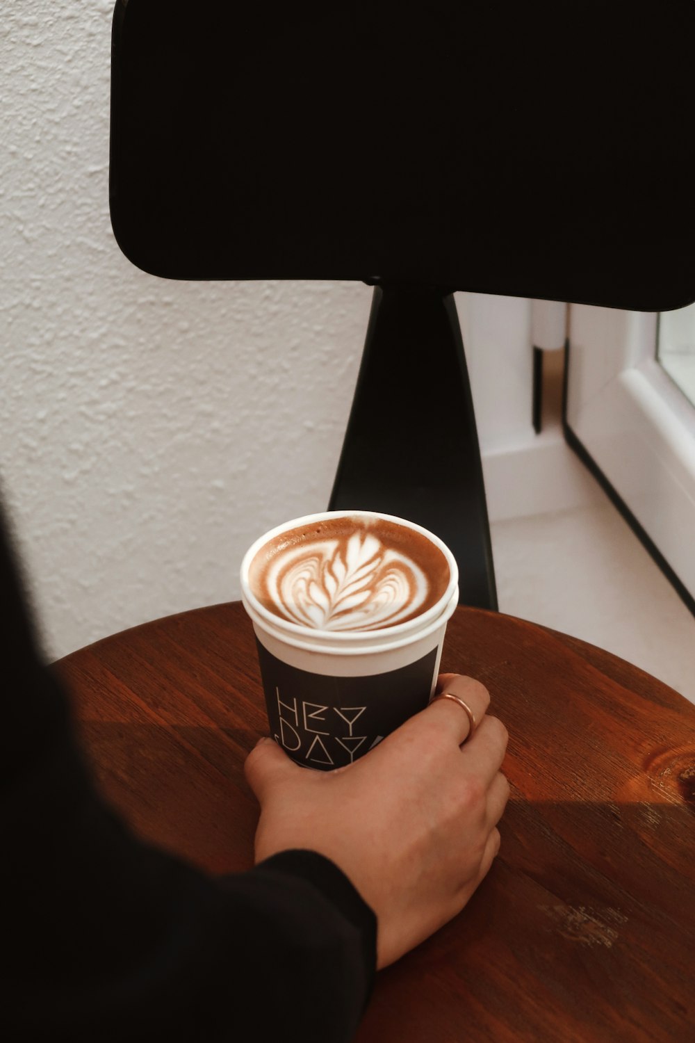 person holding black and white coffee cup