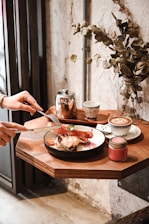 A cozy cafe table set with a plate of pasta and a drink.