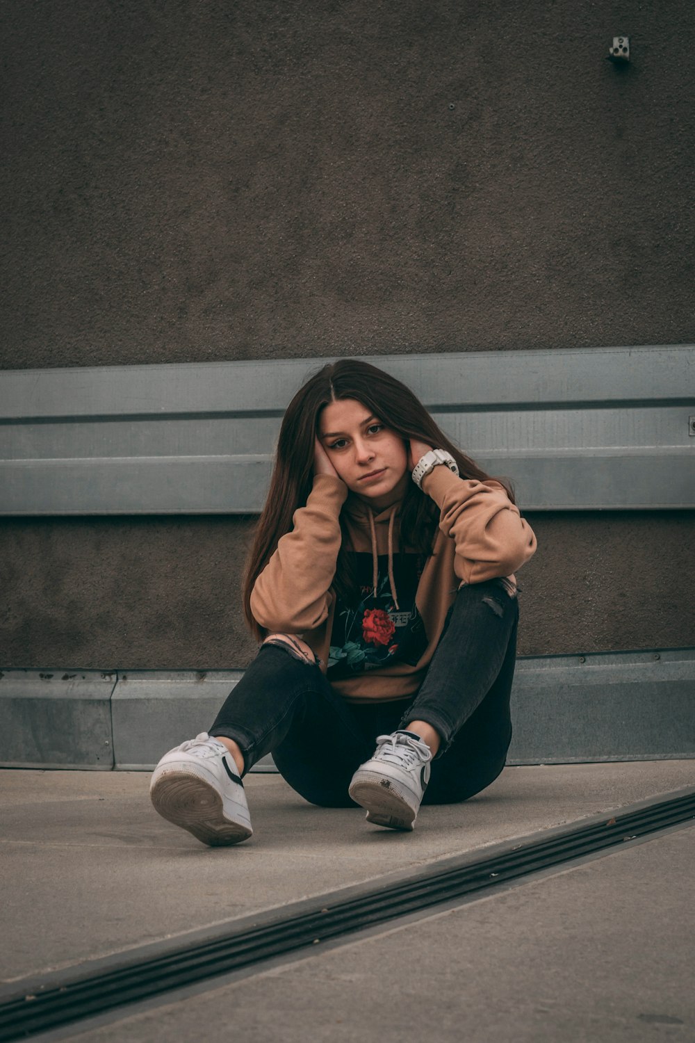 woman in brown long sleeve shirt and black pants sitting on gray concrete stairs