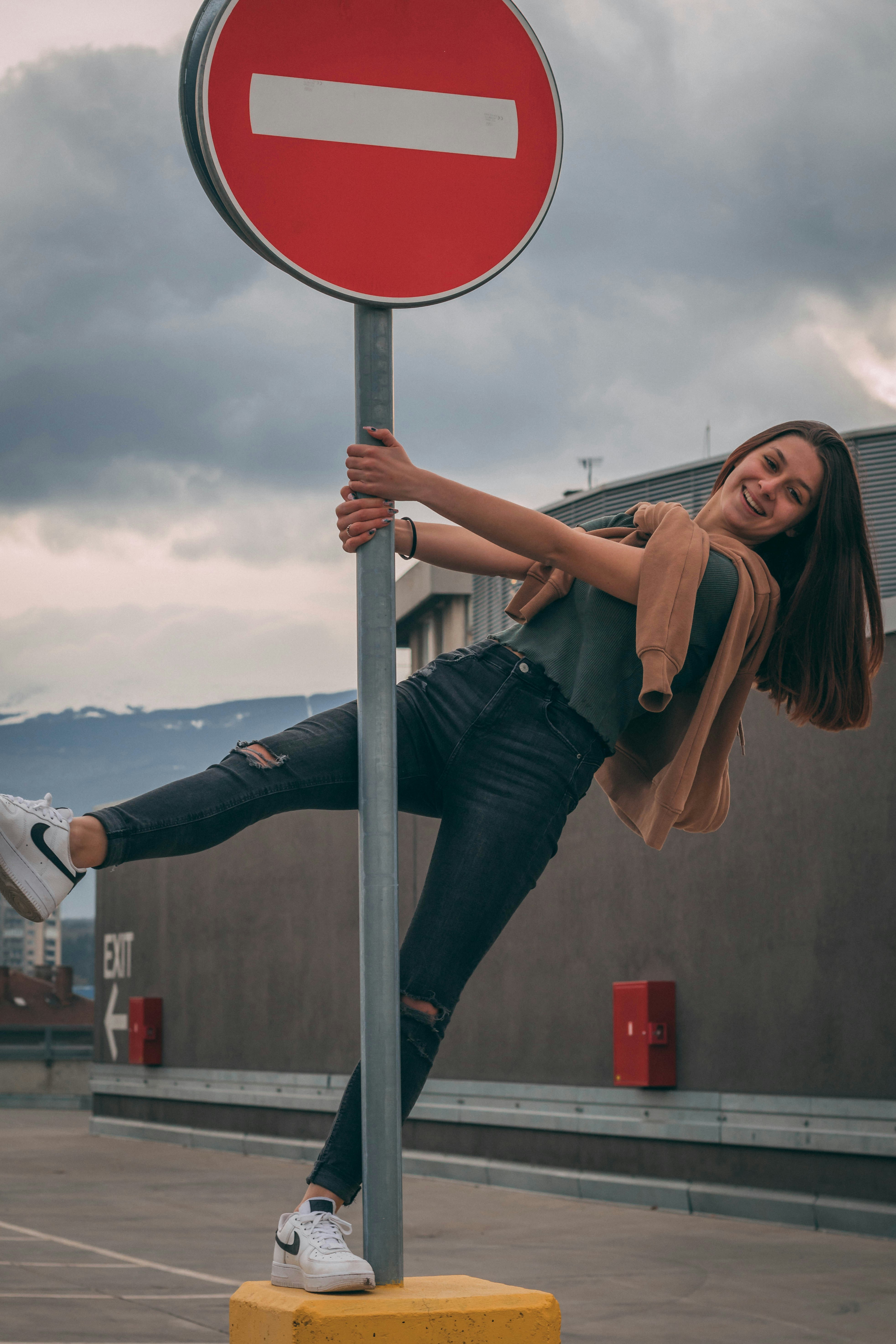 Mujer en camiseta sin mangas negra y jeans de mezclilla azul sentada en el aro de baloncesto