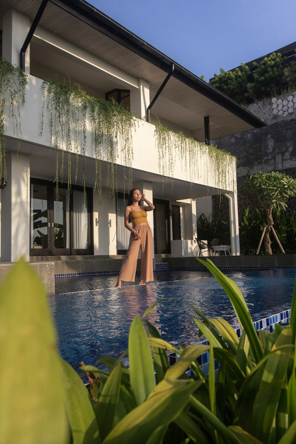 woman in brown dress standing on swimming pool during daytime