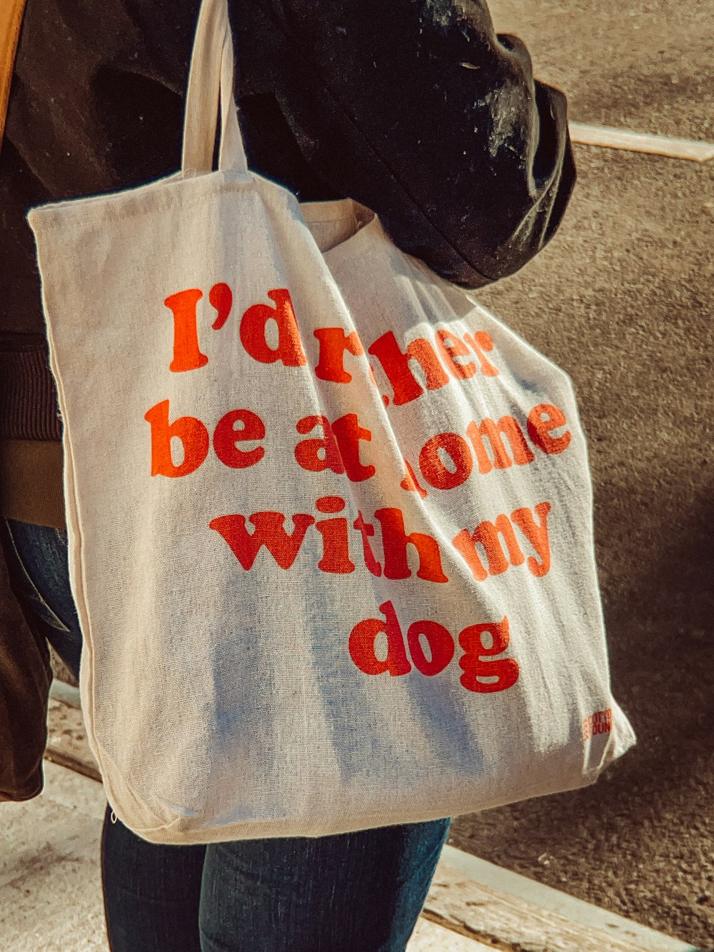 a woman carrying a tote bag that says i'd rather be at home