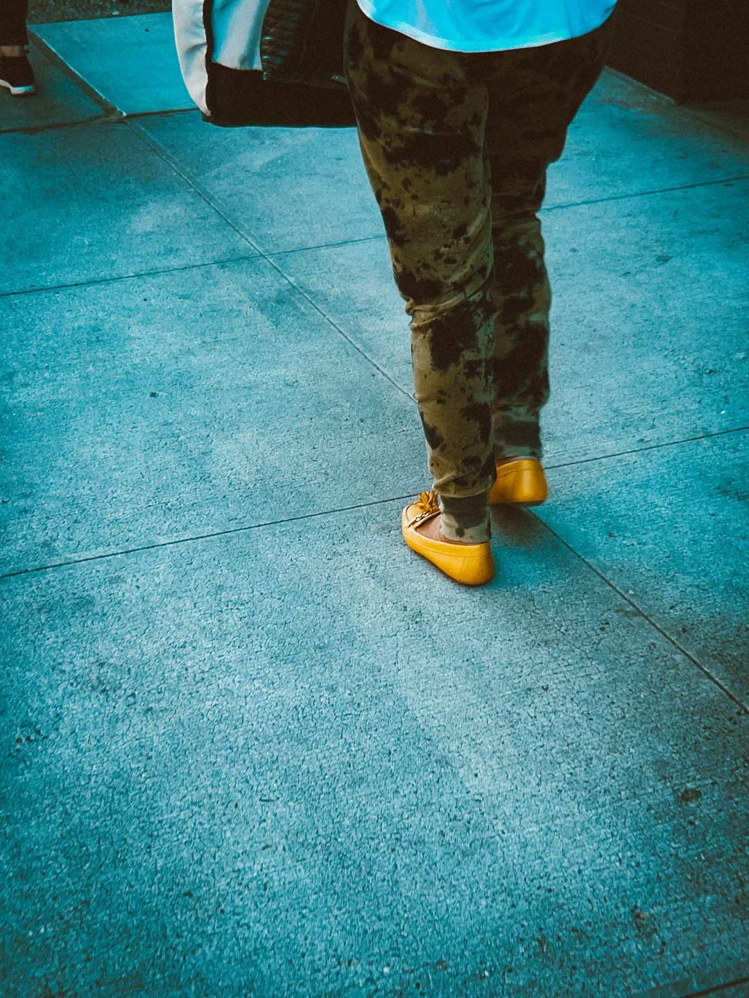 person in brown pants and yellow shoes standing on blue floor tiles