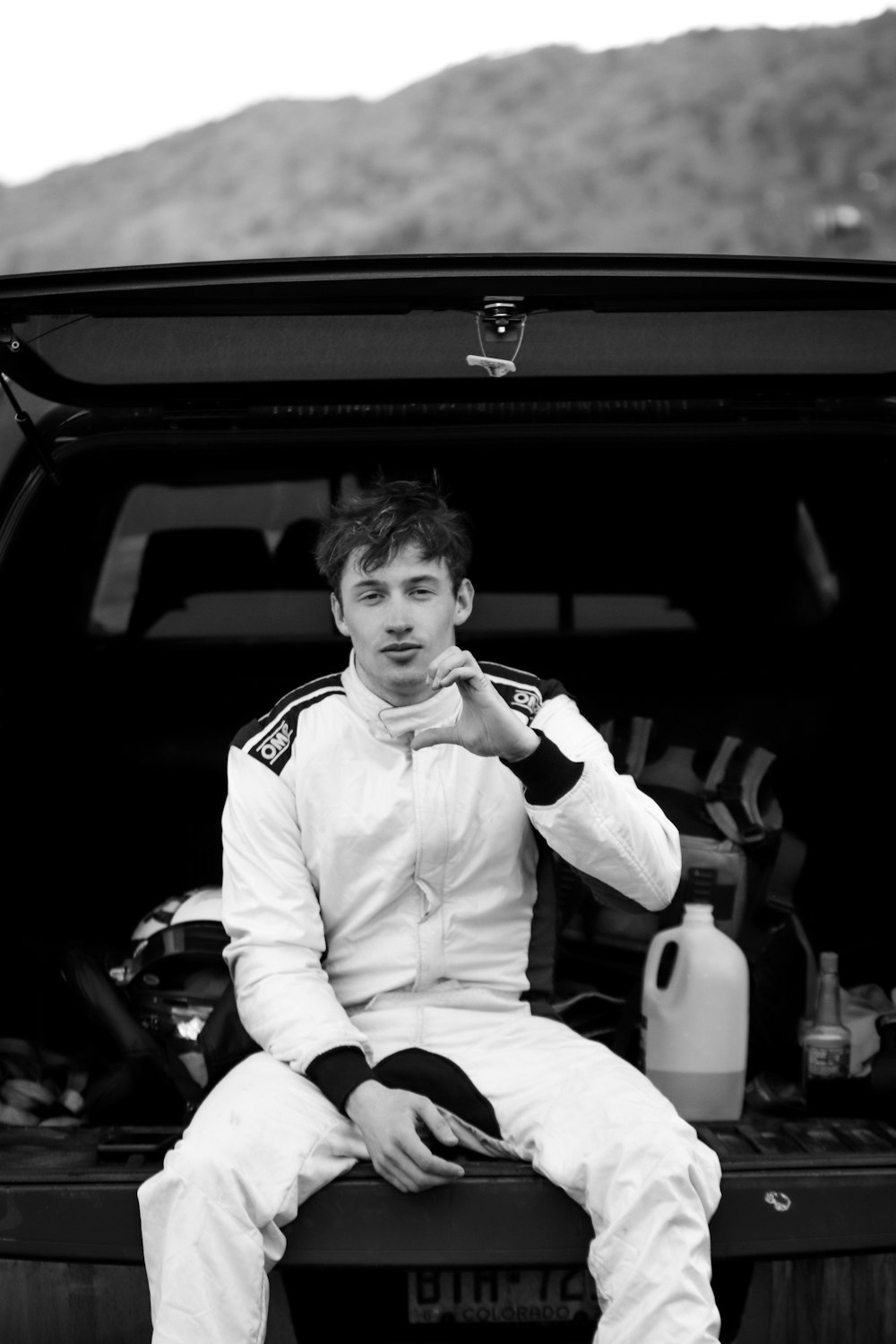 grayscale photo of boy in white long sleeve shirt sitting on car seat