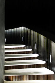Minimalist wooden staircase with floating solid walnut steps and hidden metal supports in a modern interior.