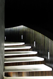 Minimalist wooden staircase with floating solid walnut steps and hidden metal supports in a modern interior.