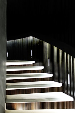 Modern staircase with floating wooden steps and metal railing in a bright space.