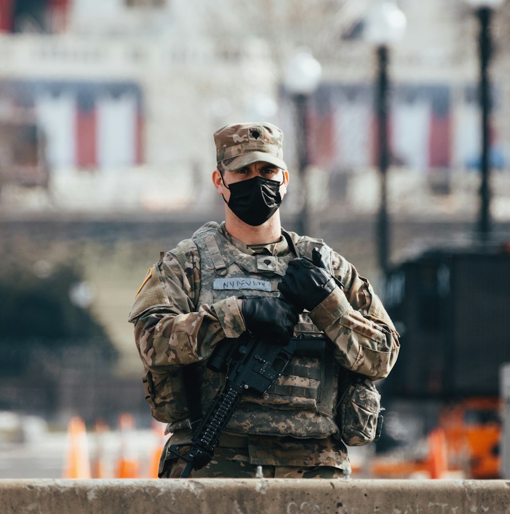 Hombre con uniforme de camuflaje negro y marrón sosteniendo un rifle