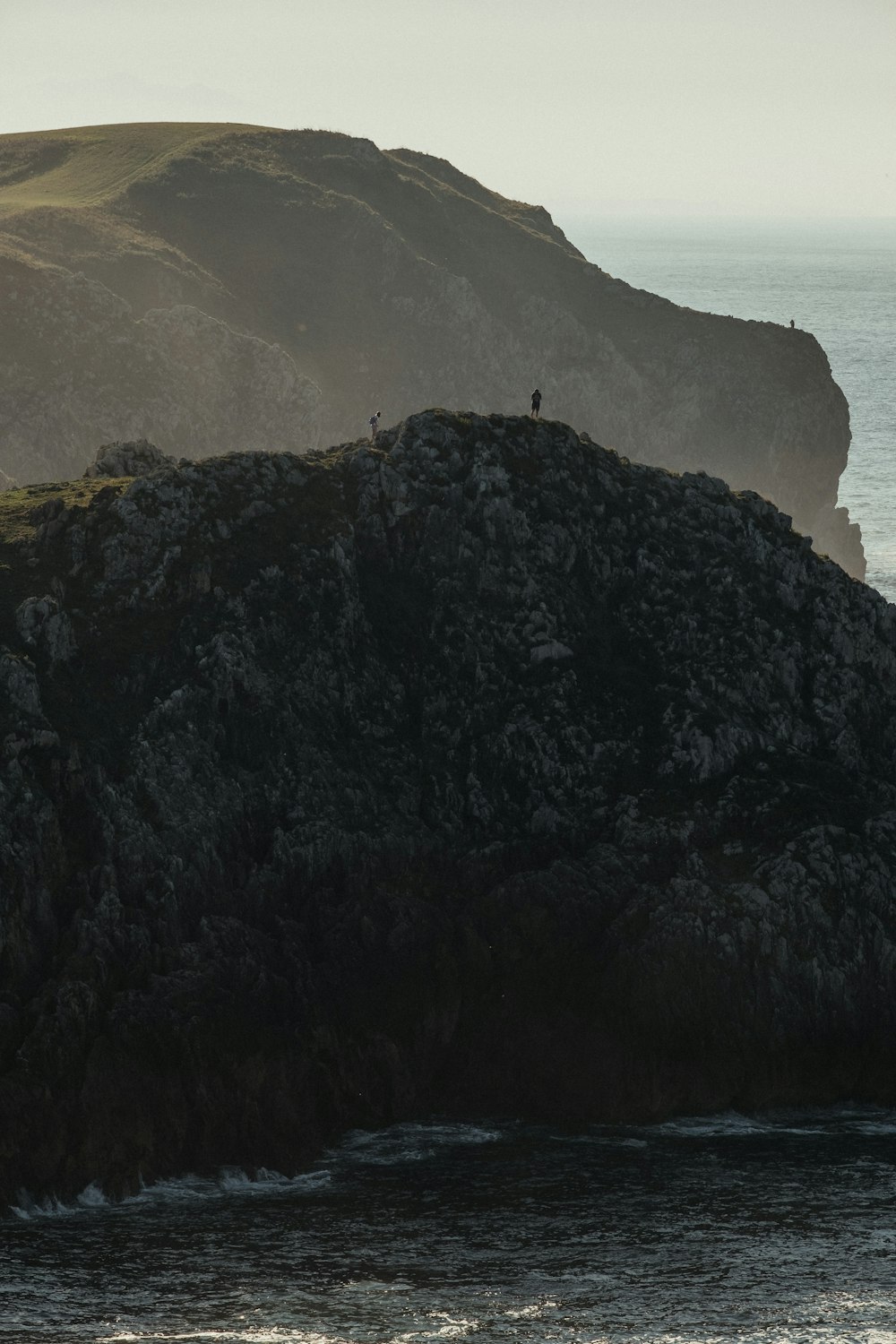 Montaña negra y marrón al lado del cuerpo de agua durante el día