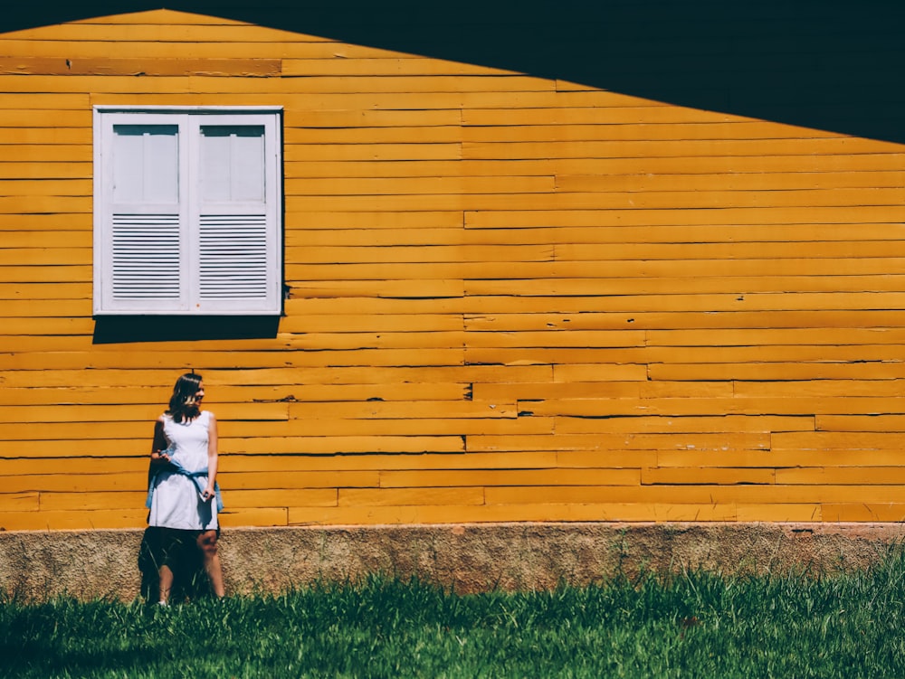 girl in white shirt and orange skirt standing on green grass field during daytime