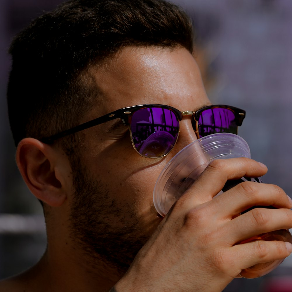 man in black framed sunglasses drinking water