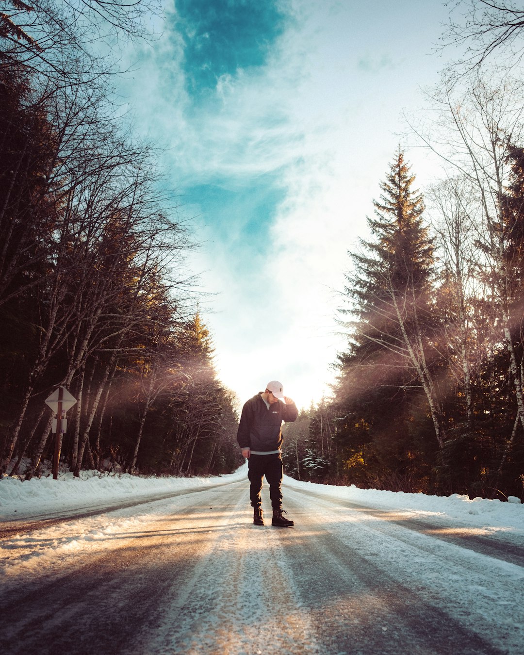 person in black jacket and black pants walking on snow covered road during daytime