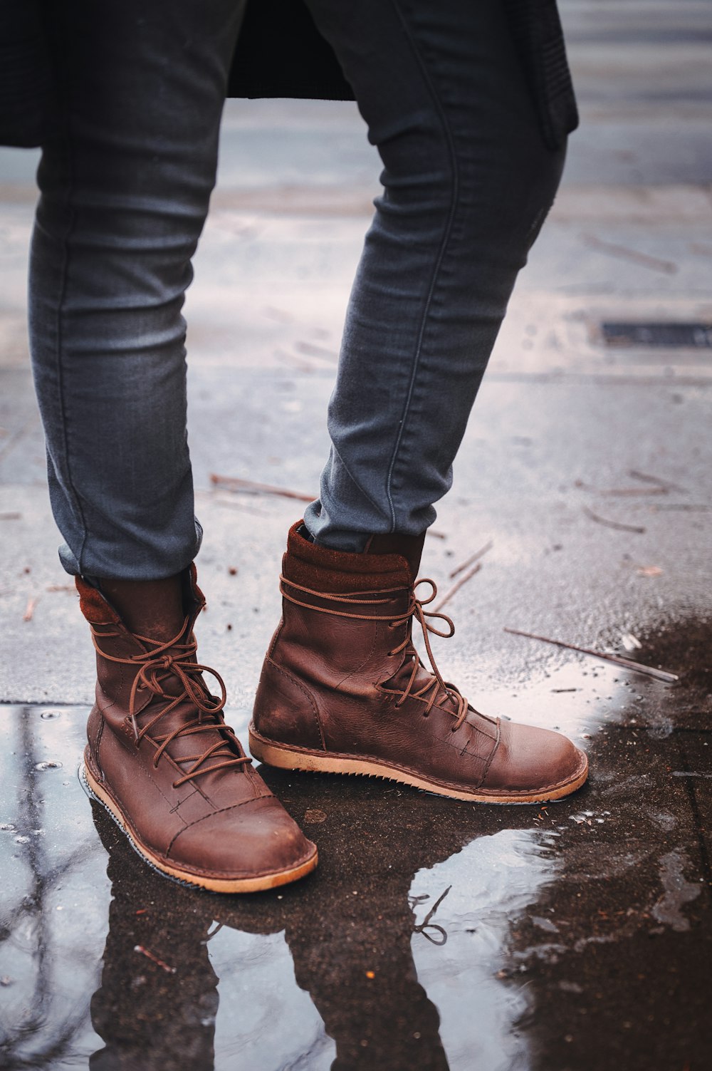 person in blue denim jeans and brown leather boots standing on gray concrete floor