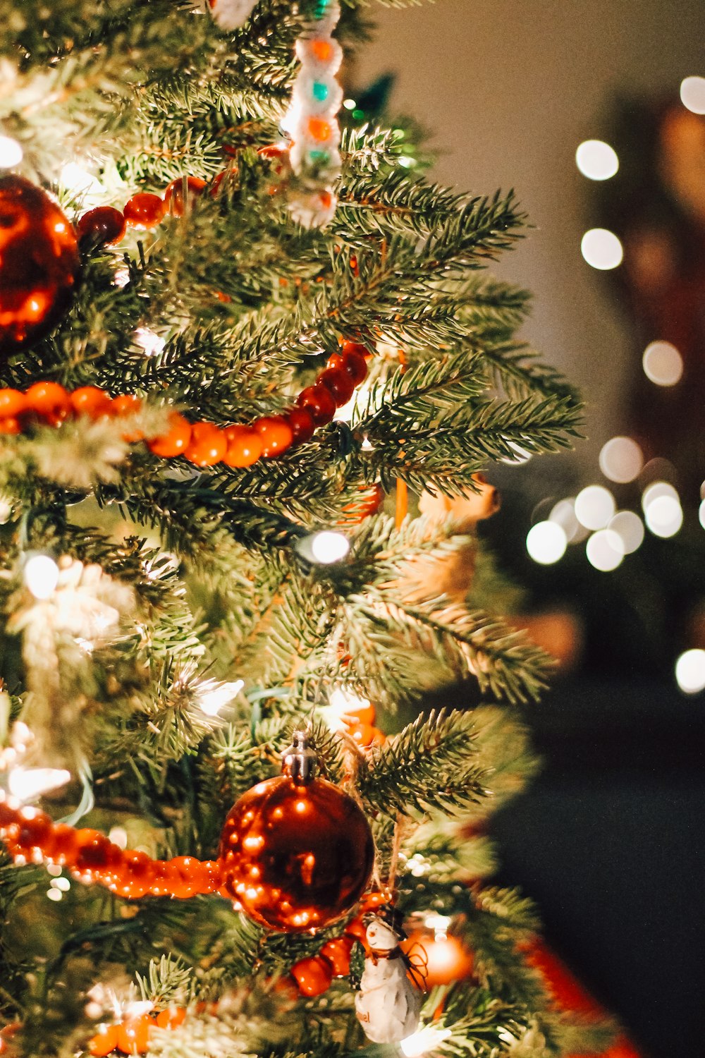 Adornos naranjas y blancos en el árbol de Navidad verde