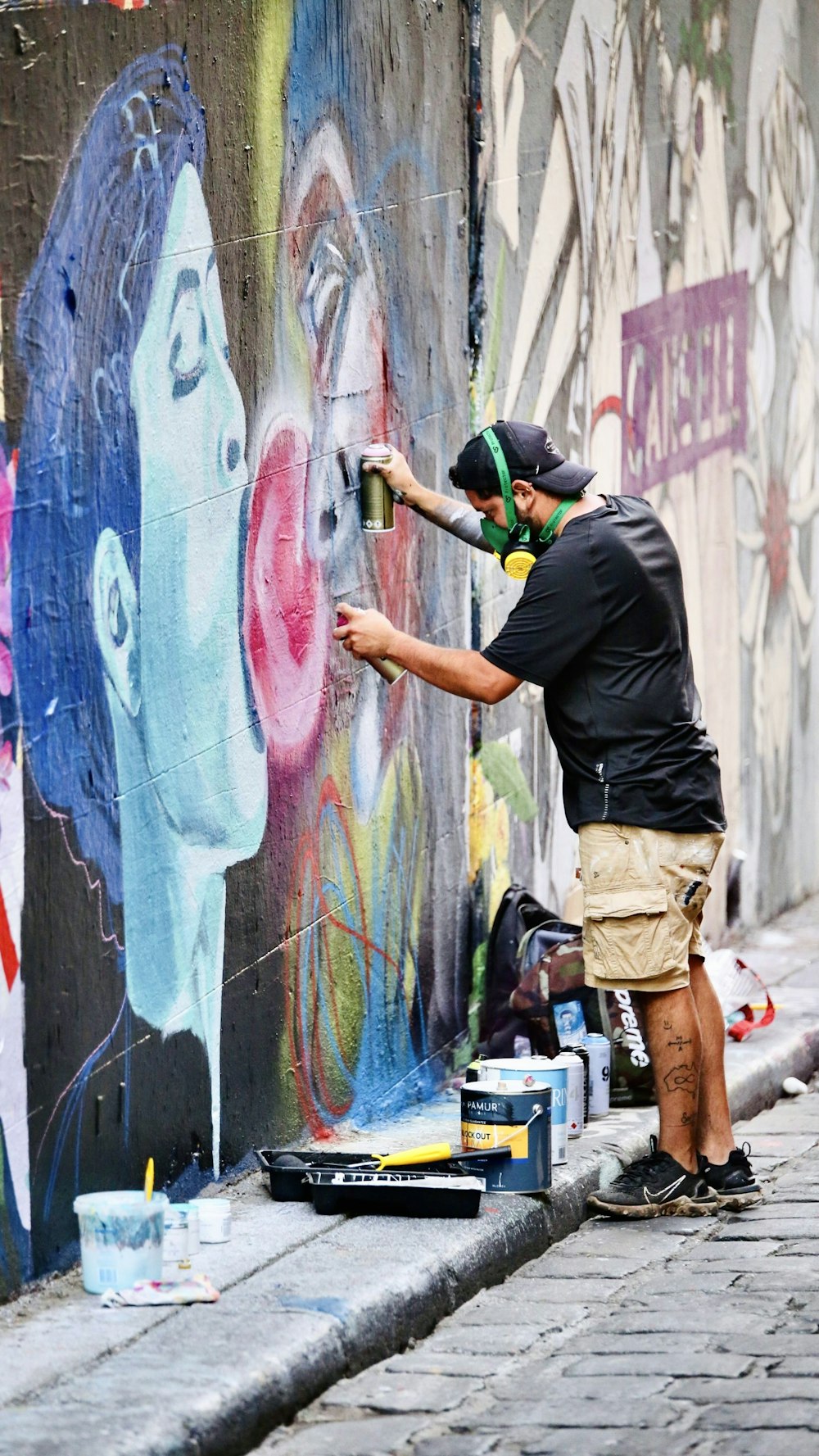 man in black t-shirt and brown shorts painting a wall