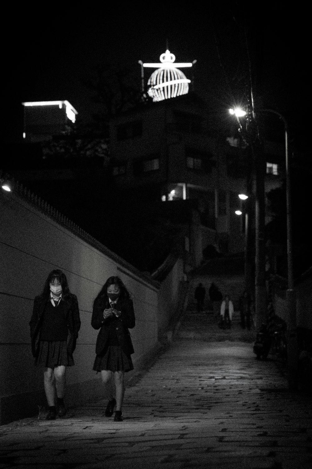 woman in black coat standing near wall during night time