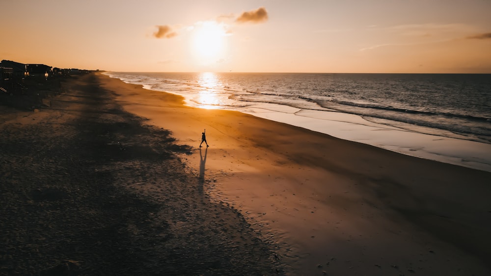 Person, die während des Sonnenuntergangs am Strand steht