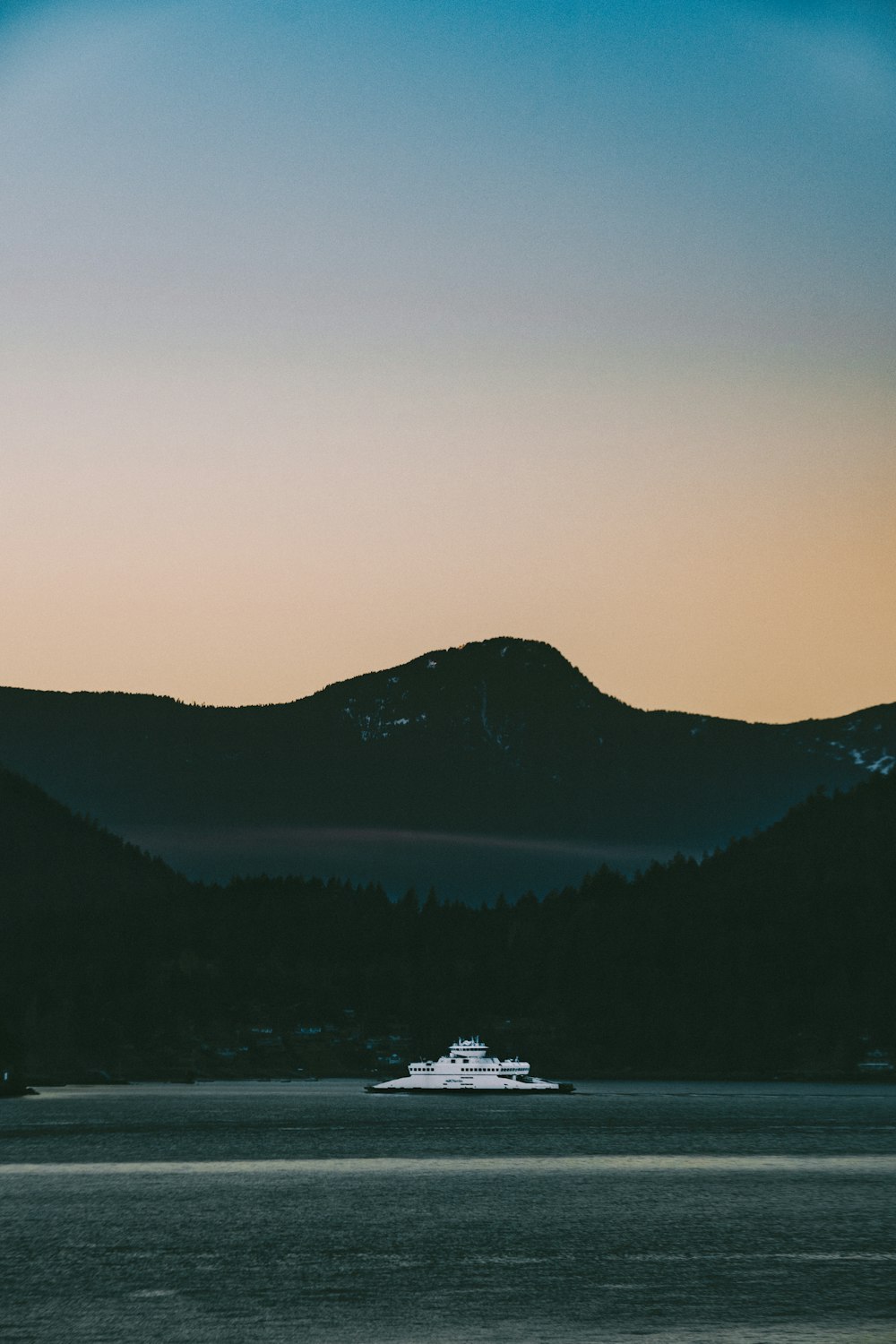 white boat on water near mountain during daytime