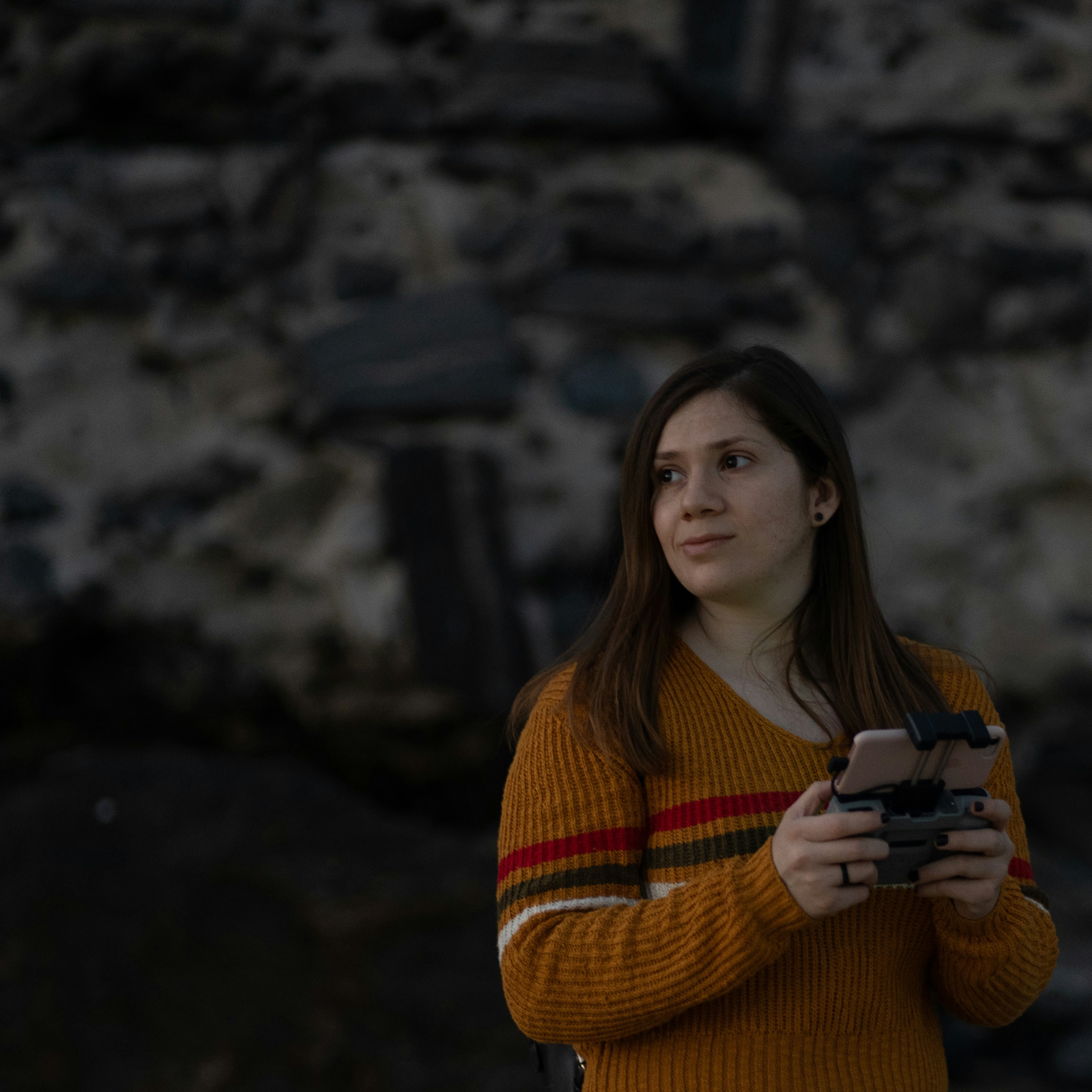 woman in orange knit sweater holding black ceramic mug
