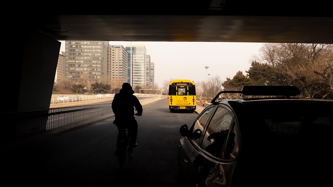 man in black jacket standing beside yellow school bus during daytime