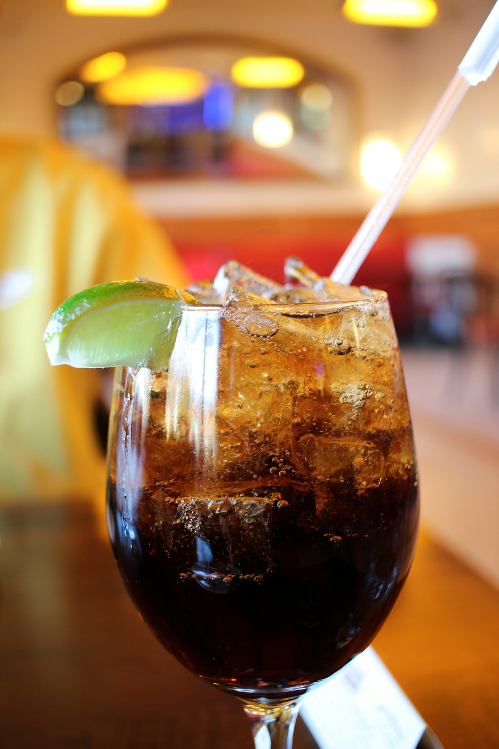 clear drinking glass with brown liquid and straw