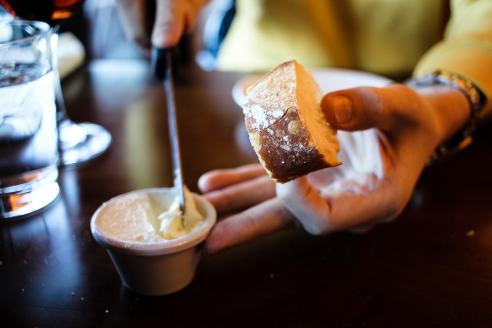 person holding bread with white cream