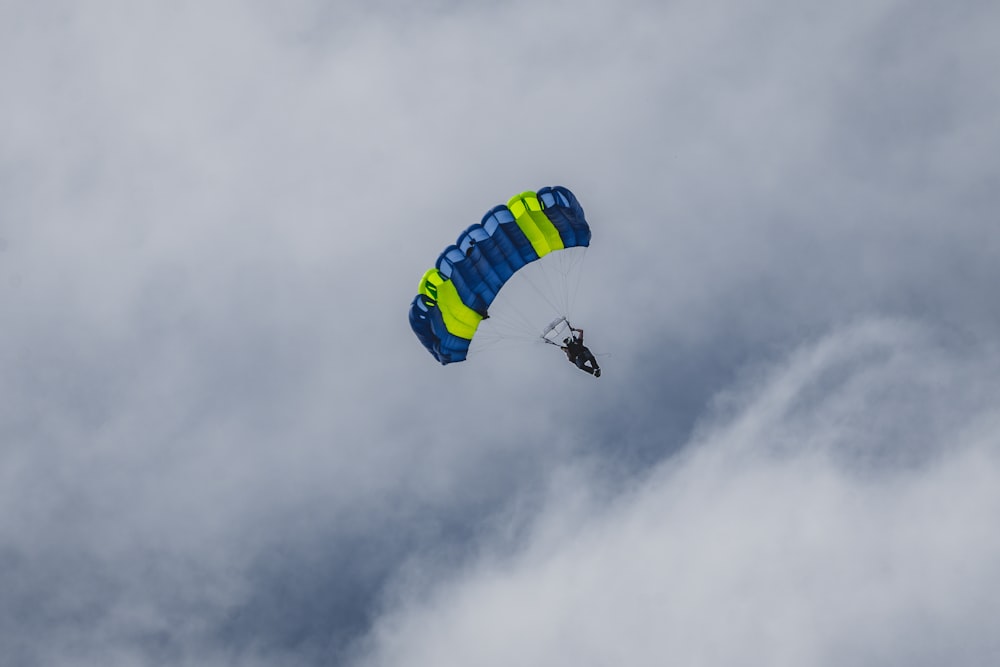person in yellow parachute under white clouds during daytime