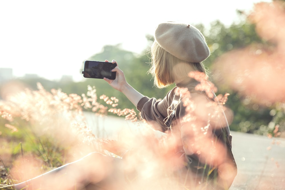 woman in black jacket taking photo of white clouds during daytime