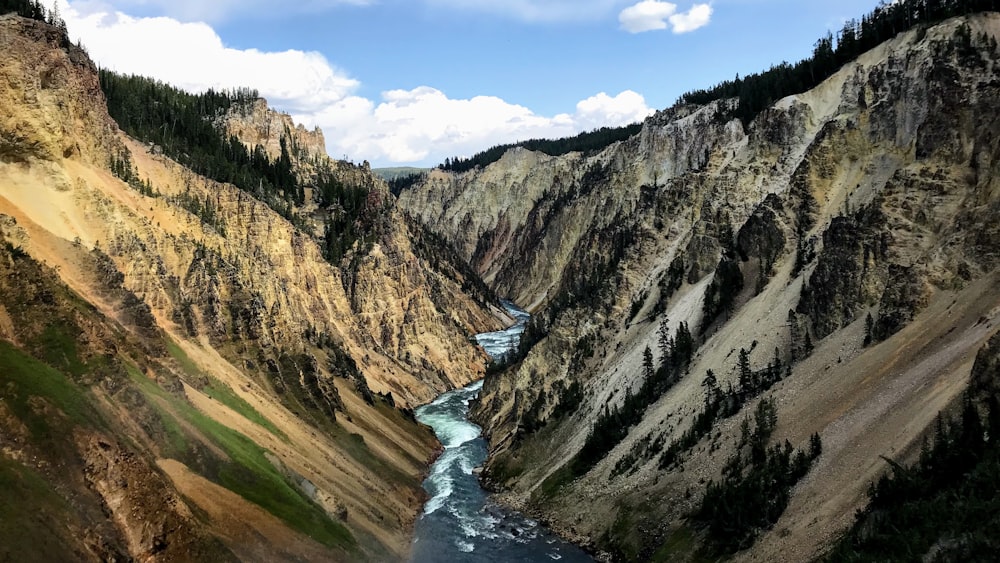 river between mountains under blue sky during daytime