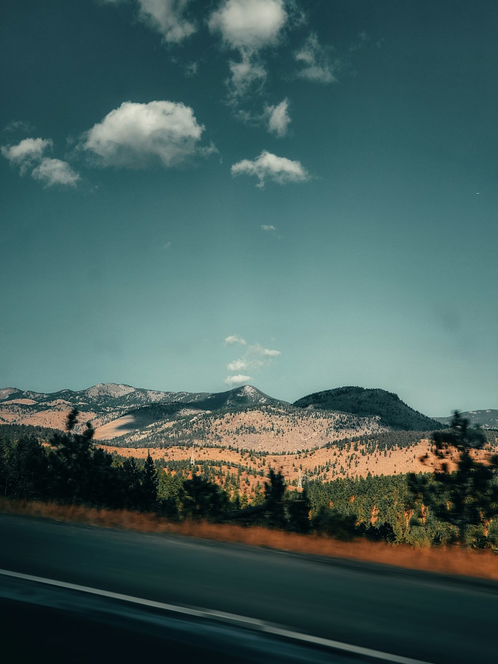 green trees near mountain under blue sky during daytime