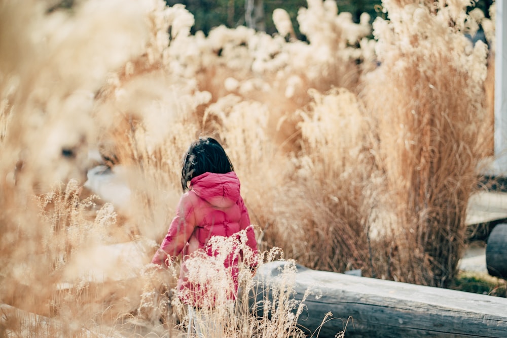 woman in pink dress sitting on brown wooden log during daytime