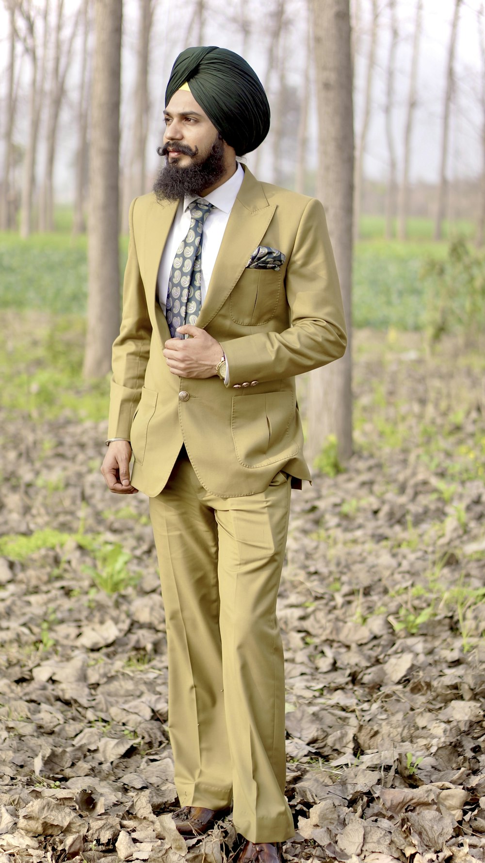 man in brown suit jacket and brown pants standing on brown soil during daytime