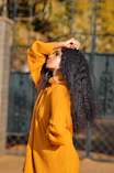 woman in yellow knit sweater covering her face with her hair