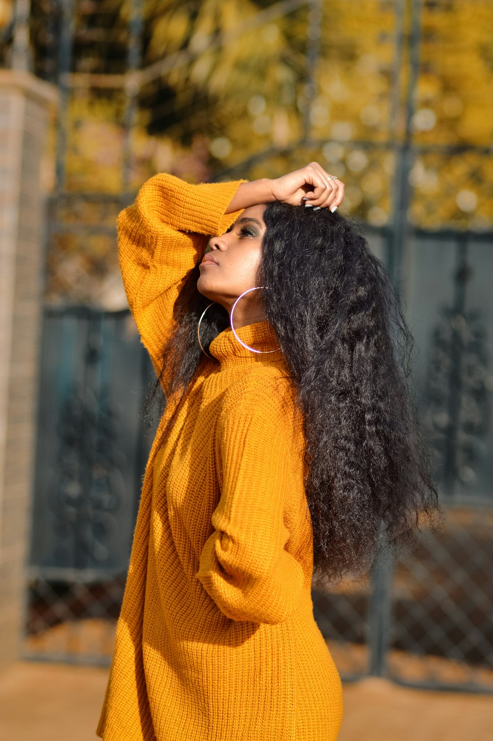 woman in yellow knit sweater covering her face with her hair