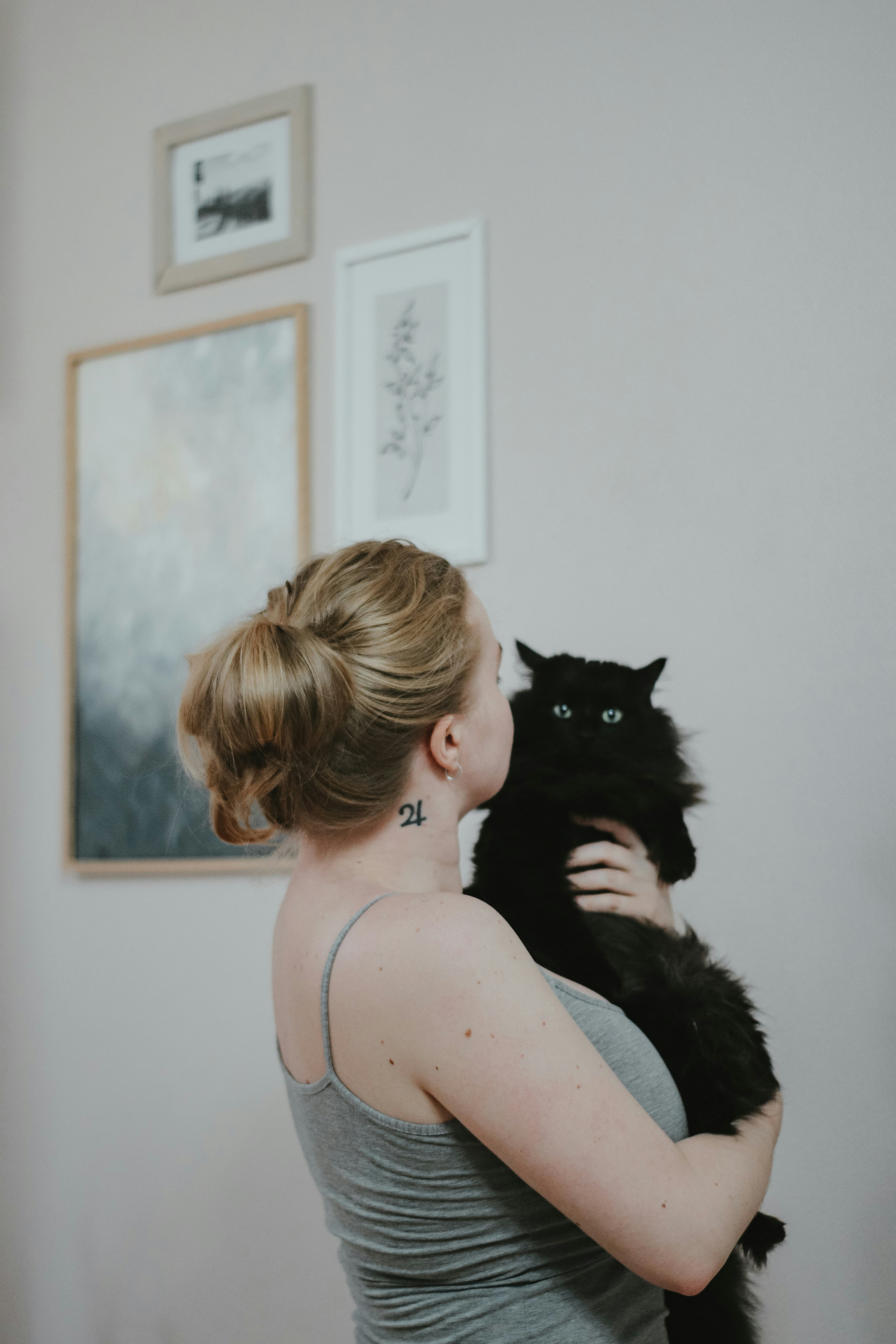 woman in black tank top beside black cat