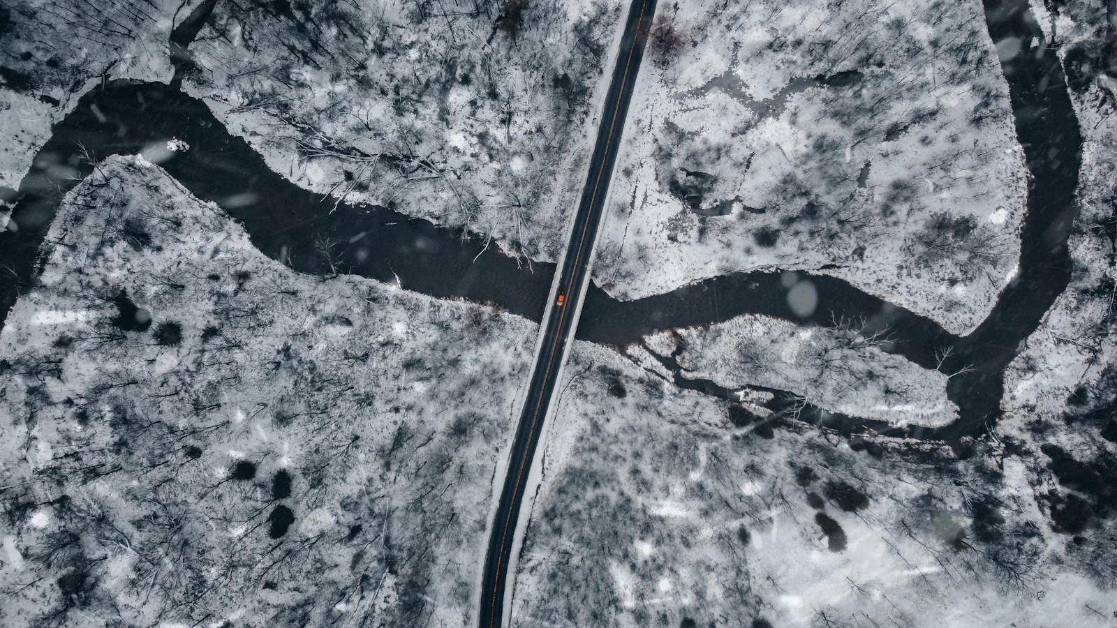 A dark car travels along a snowy road in Toronto