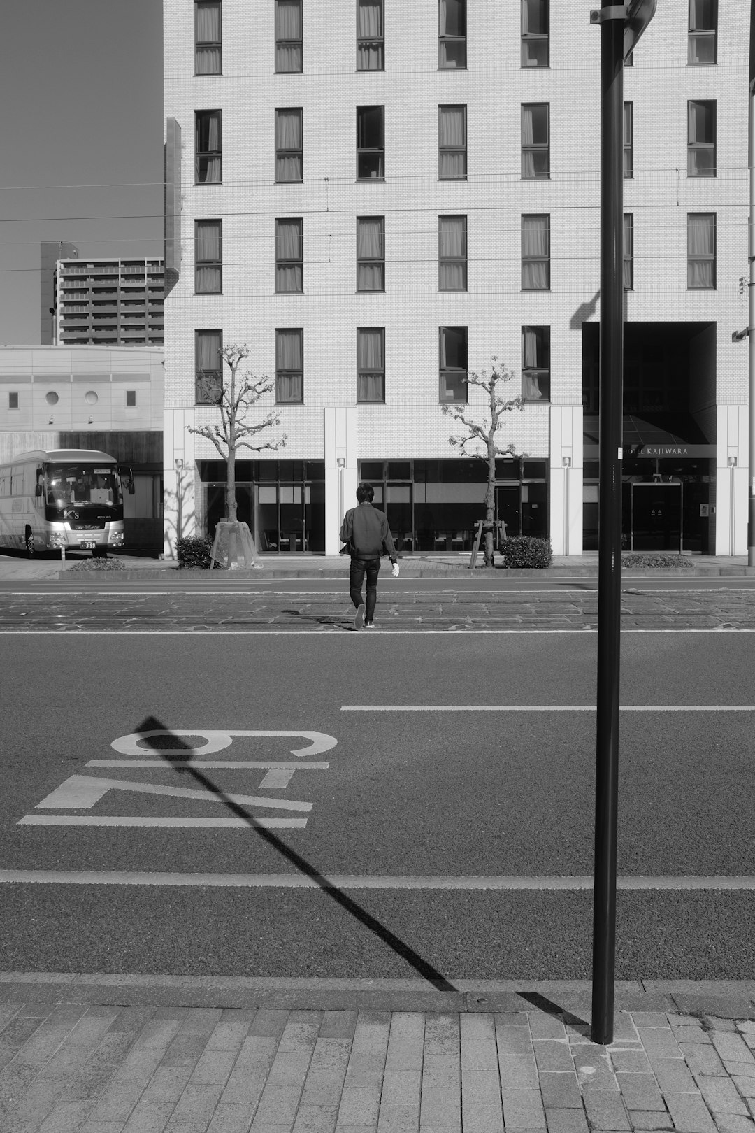 grayscale photo of man walking on pedestrian lane