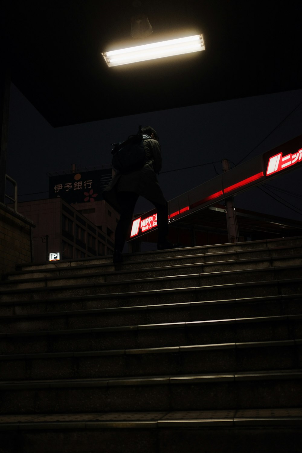 회색 콘크리트 계단에 검은 재킷과 검은 헬멧을 쓴 남자