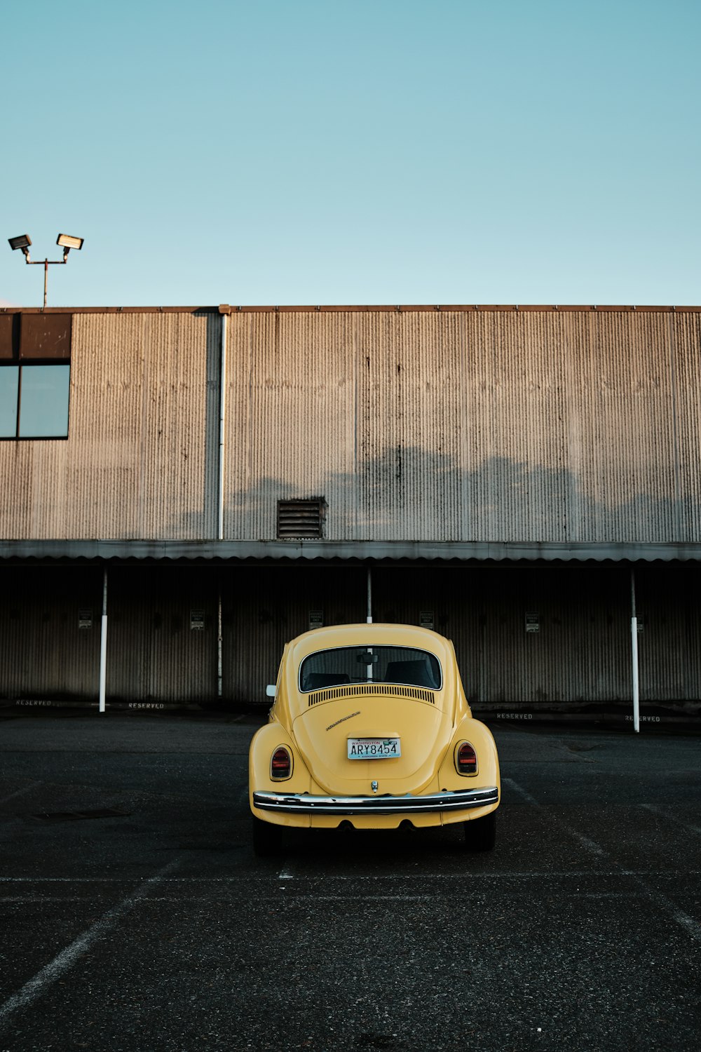 yellow porsche 911 parked beside brown building