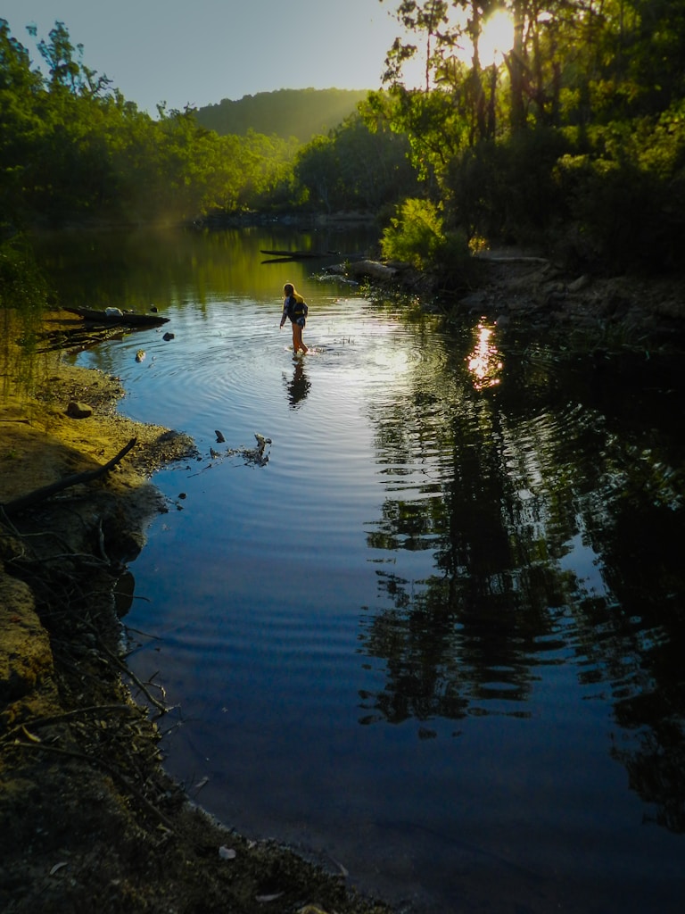 man in black shirt and black shorts standing on river during daytime