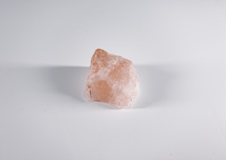 A rough, semi-transparent mineral rock with a pinkish hue against a plain white background.