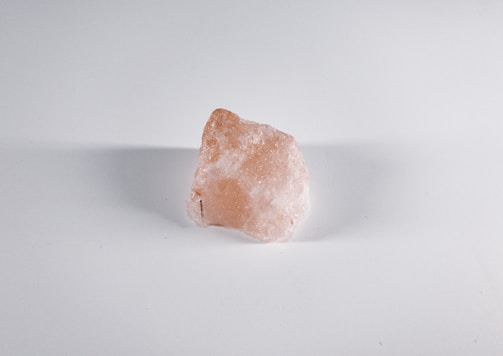 A rough, semi-transparent mineral rock with a pinkish hue against a plain white background.