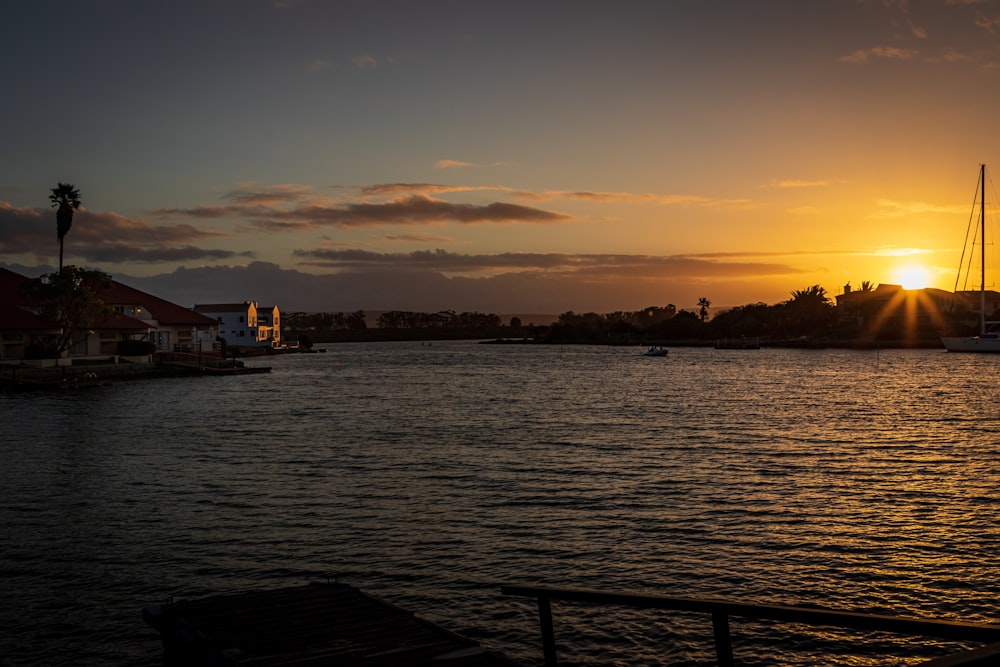 body of water near city buildings during sunset