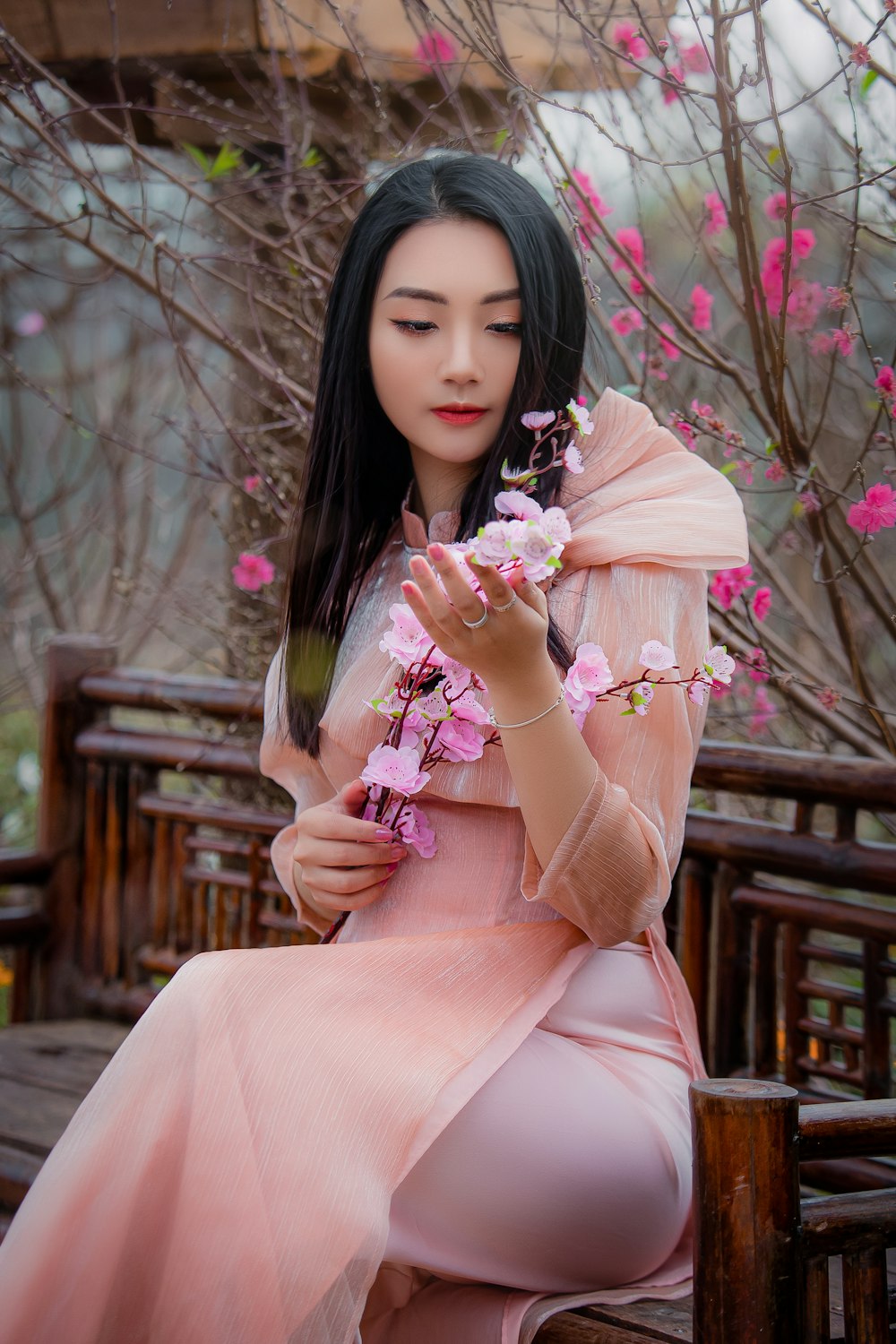 woman in pink long sleeve dress holding pink flowers