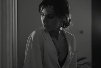 A woman looking thoughtful and uncertain in a softly lit room.