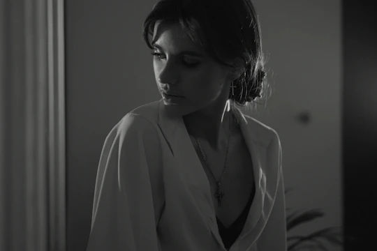 A woman looking thoughtful and uncertain in a softly lit room.