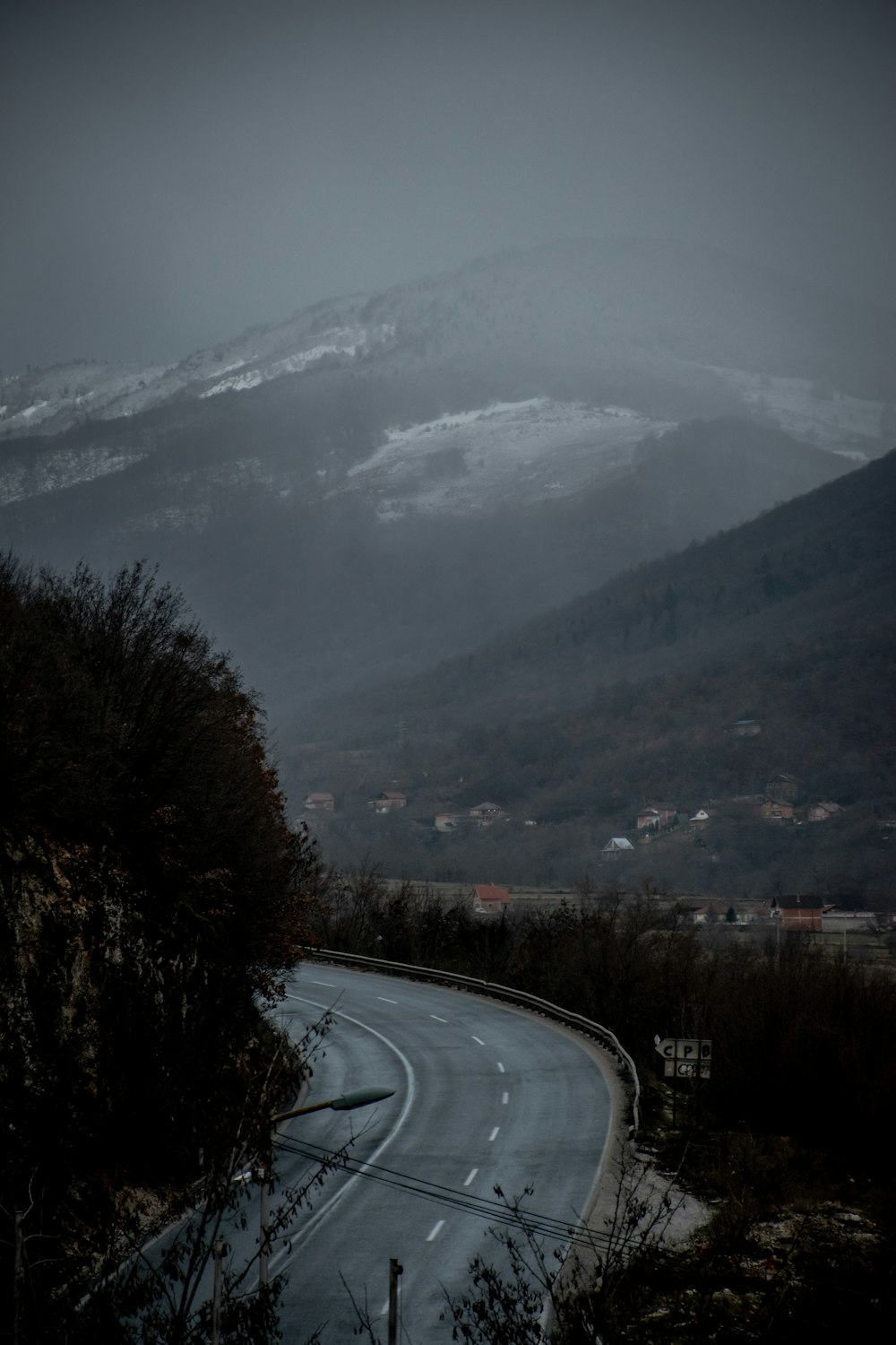 gray asphalt road between trees and mountains during daytime