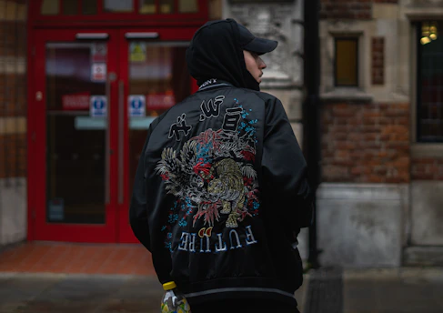 man in black hoodie and black pants walking on sidewalk during daytime