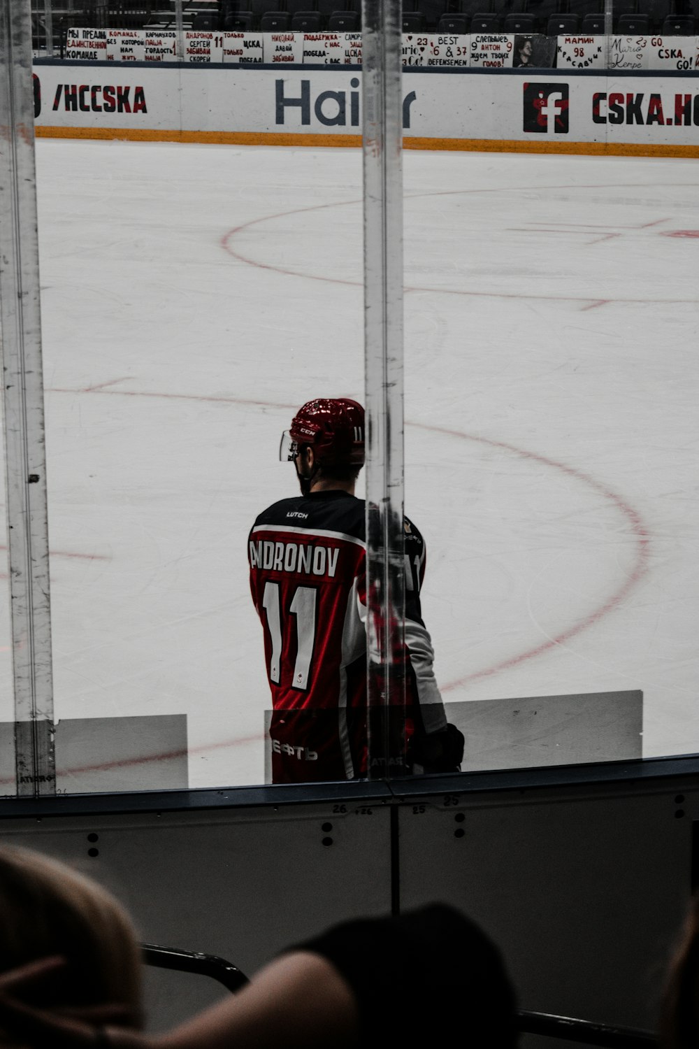 man in red and white jersey shirt and black pants standing on ice hockey field