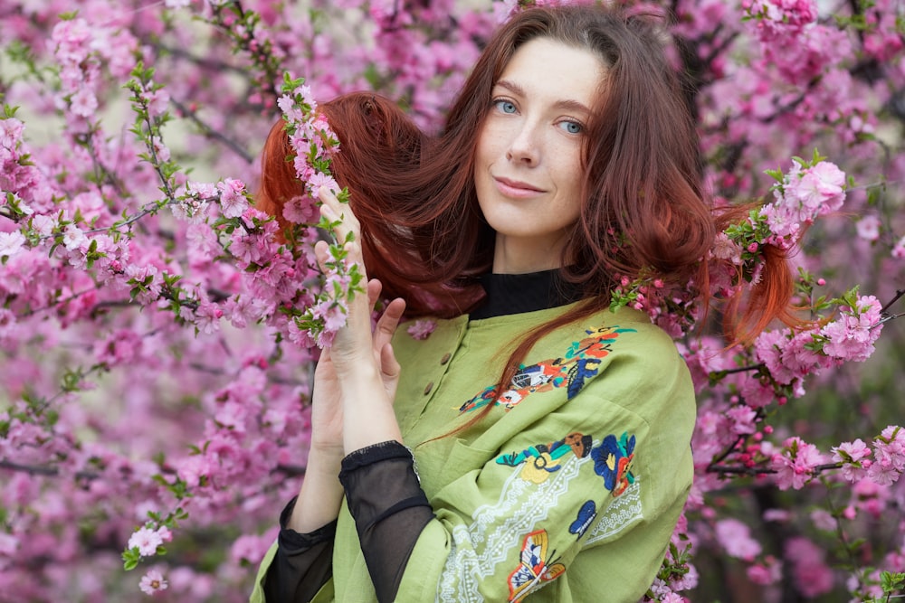 woman in green and yellow long sleeve shirt holding pink flowers